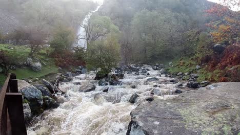 cascada rocosa que fluye a cámara lenta agua del río salpicando en la formación rocosa de la ribera del bosque