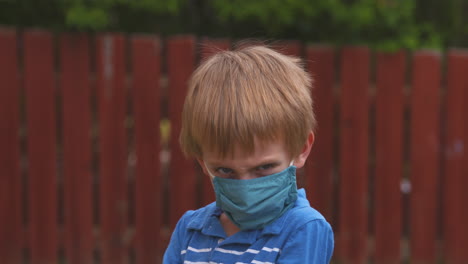 portrait of a little boy unhappy to be wearing a protective face mask