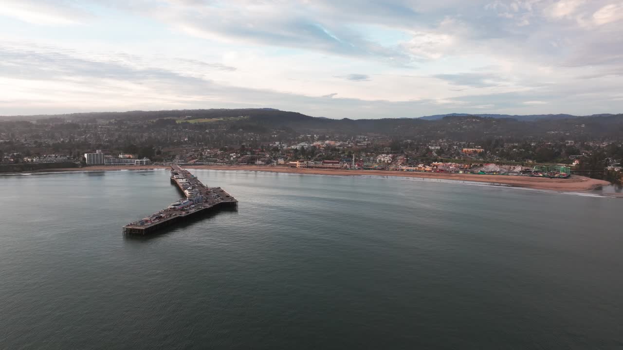 해가 지는 동안 산타 크루즈 해변을 향해 날아오는 드론의 공중 촬영