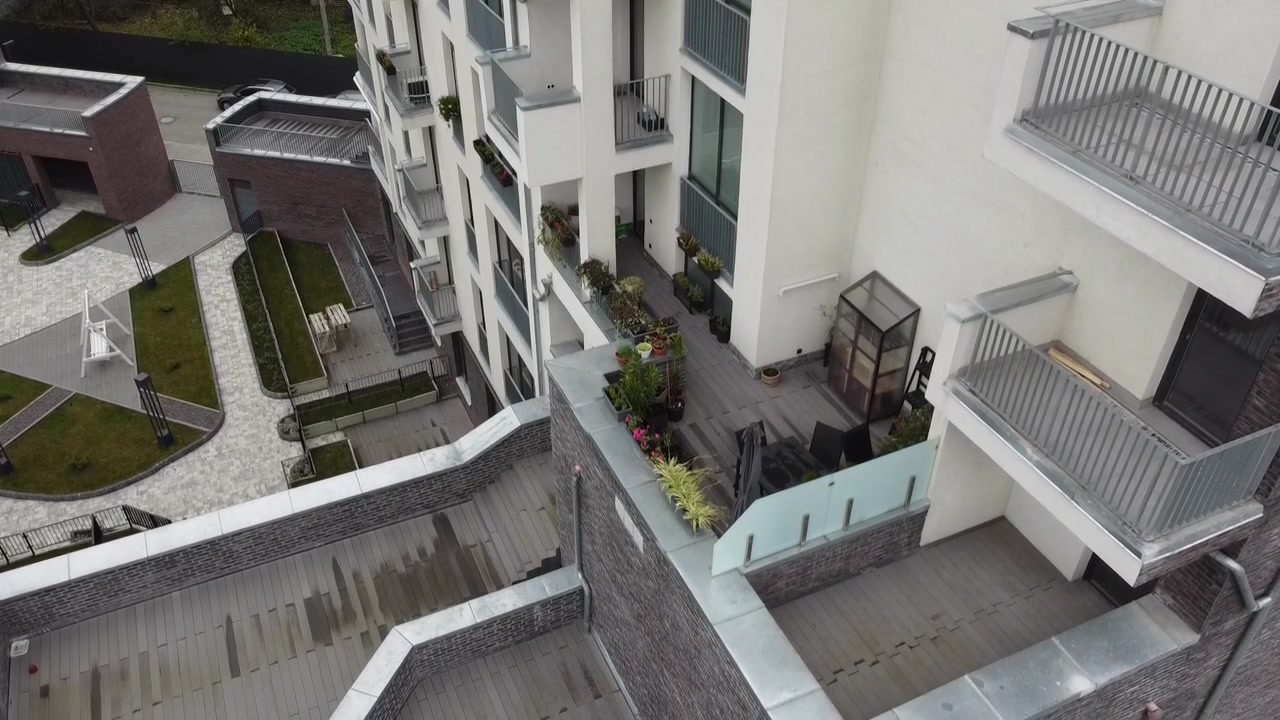 Luftfoto af en drone, der flyver over boligbygninger, med optagelser af tage og arkitektur.