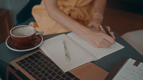 woman writing in a notebook at a cafe