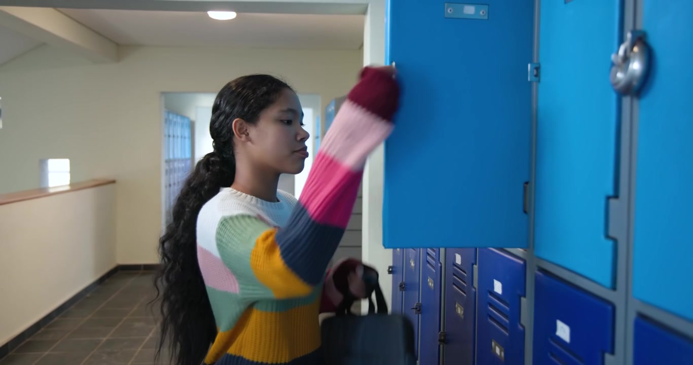 Asian girl child walking through school hallway after class, opening locker and retrieving backpack