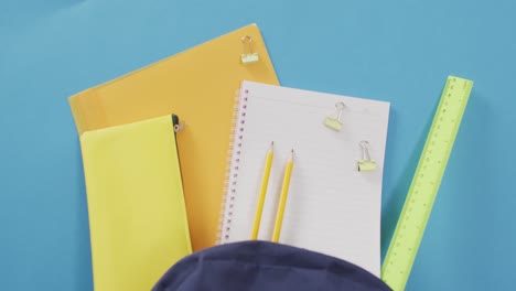 video of school supplies, notebook, pens, ruler, paper clips over blue background