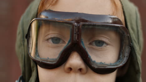 close up of a little red haired boy in aviator glasses looking and smiling at camera