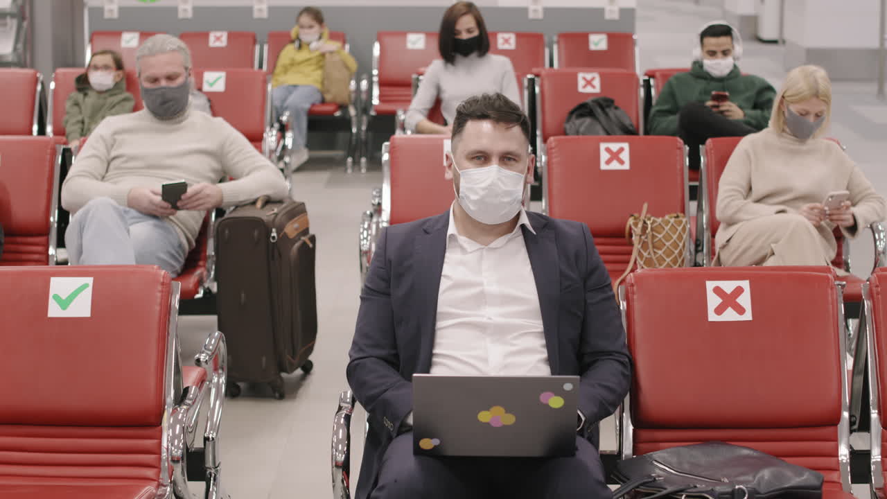 Businessman Sitting In Departure Lounge With Laptop