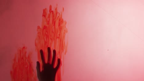 video of silhouette of hand with blood stains moving on red background