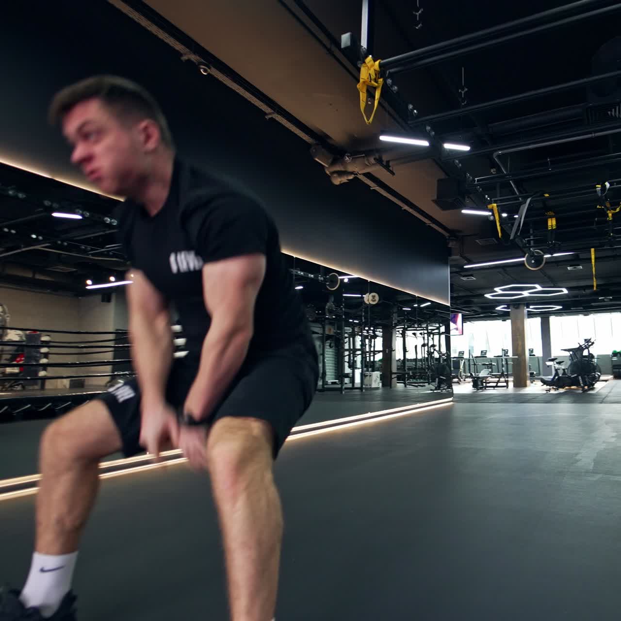 Strongman quickly performing exercise with ropes. Man aggressively throws the ropes and walks away along the sport gym