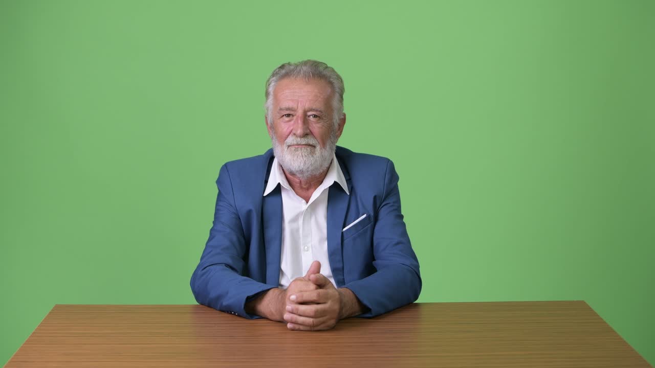Affascinante uomo d'affari anziano con barba su sfondo verde
