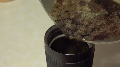 verter lodo líquido verde-marrón en una taza de prensa francesa para hacer mantequilla casera