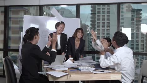 successful asian business people celebrate project success in group meeting.