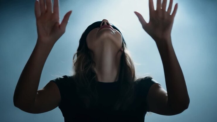 Blindfolded woman raises her hands, searching for direction in a dark blue environment filled with mystery and uncertainty