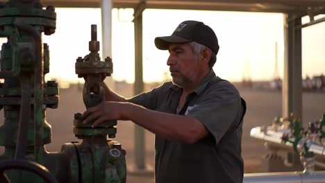 an oil field technician carefully inspects and adjusts equipment at sunset, ensuring operational efficiency and safety in the energy sector