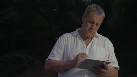hombre escribiendo en la tableta en el crepúsculo