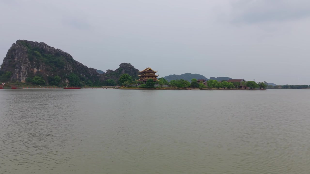 Chuyến bay drone thấp tiếp cận chùa Phật giáo Chùa Vàng nằm trên một hòn đảo được bao quanh bởi làn nước yên tĩnh tại Ninh Bình, Việt Nam