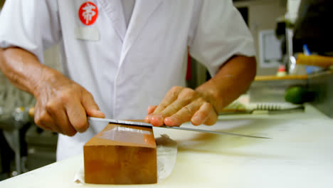 male chef sharpening knife on a whetstone in kitchen 4k