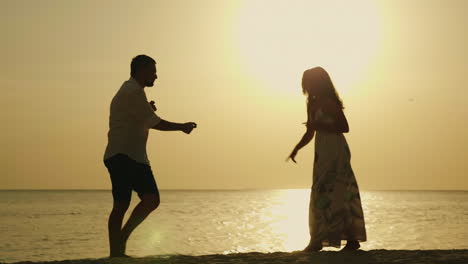 Silhouettes-Of-A-Young-Couple-Cool-Dancing-Against-The-Backdrop-Of-The-Sea-And-The-Setting-Sun-Merry