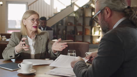 senior man and woman discussing business contract in restaurant