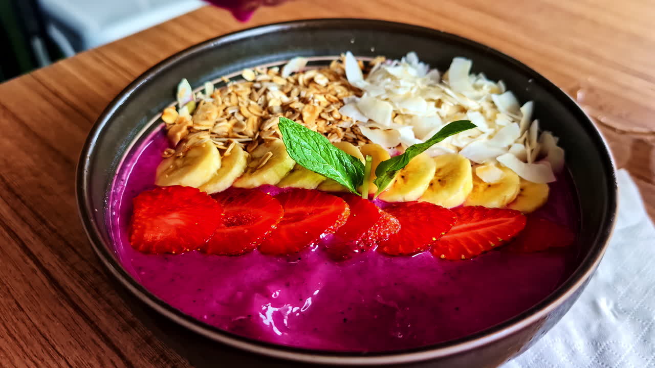 Bright smoothie bowl topped with fruits and granola, served at Amed Beach, Bali