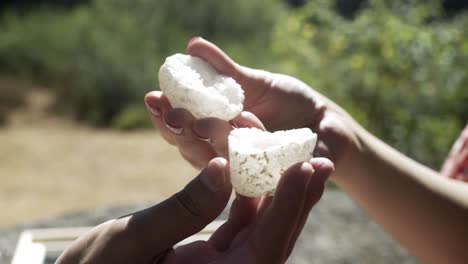 un hombre presenta a una mujer con un vestido rosa y una roca hueca blanca, que la mujer descubre desde arriba