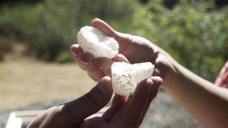 a man presents a woman wearing a pink dress and a white hollow rock, which the woman uncovers from the top