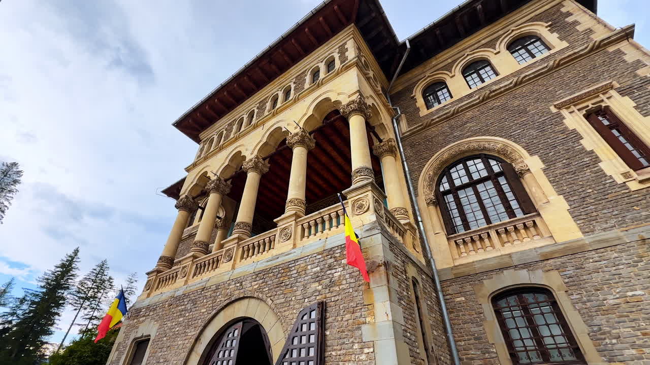 Busteni, Romania, 17 July 2025: Façade of the old building with columns and flags. Low angle perspective on Cantacuzino Castle, Busteni, Romania