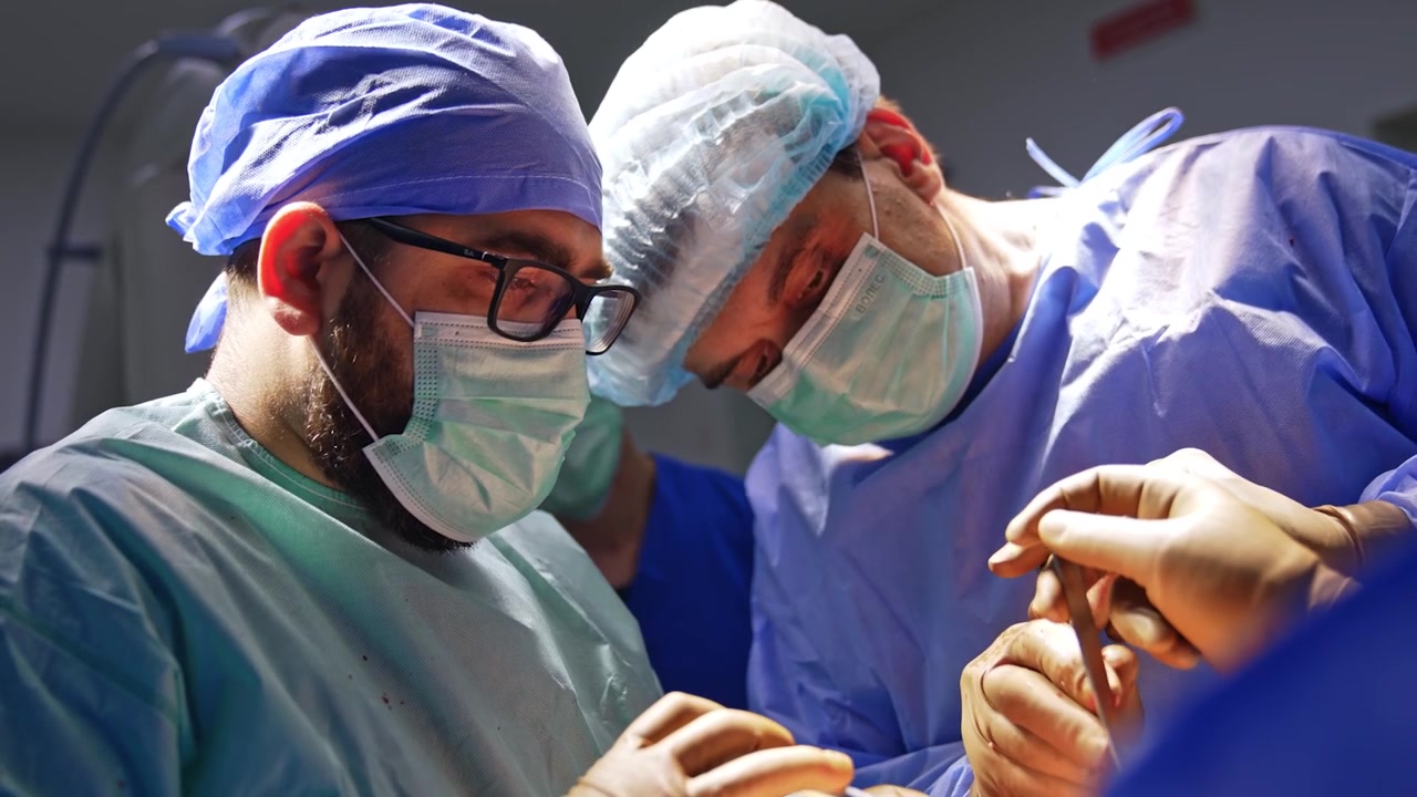Chirurghi uomini caucasici al lavoro che collaborano in chirurgia traumatologica. I medici utilizzano strumenti metallici durante l'operazione.