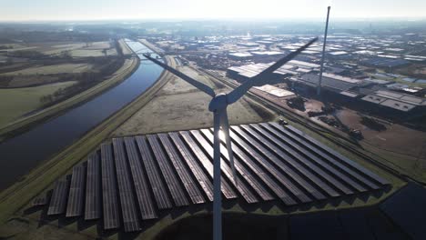 Reflection-on-solar-panels-with-windmill-turbine-in-the-foreground-and-bio-mass-and-water-cleaning-facility-in-The-Netherlands-part-of-sustainable-industry-aerial-circular-economy-concept