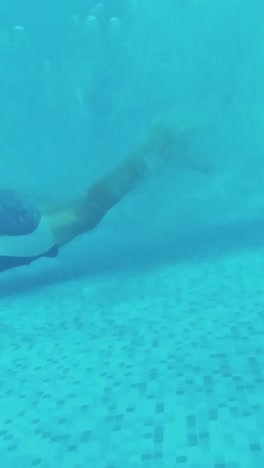 un joven nada bajo el agua en una piscina.