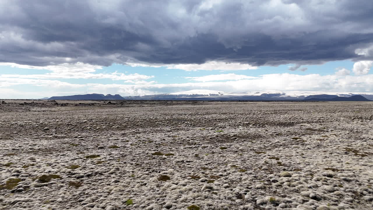 Vast Icelandic moss-covered plains leading to Mýrdalsjökull glacier under heavy dramatic storm clouds and distant mountains