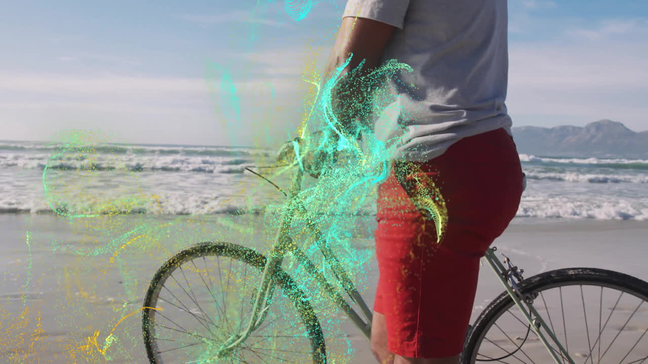 Mature adult man pausing with bicycle by shore, showing swirling digital particles for tech