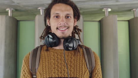 retrato de un joven de raza mixta con rastas con auriculares sonriendo feliz