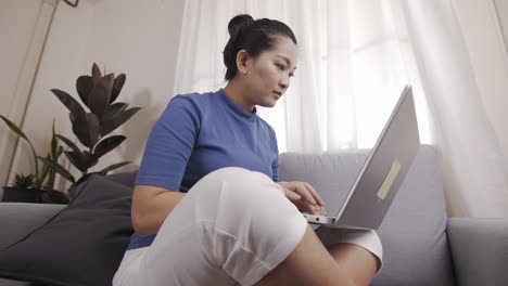toma auténtica de una mujer de negocios asiática usando una computadora portátil para trabajar felizmente desde casa