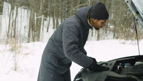 hombre atrapado en el bosque de invierno teniendo problemas con su auto