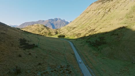 Vista-Aérea-Por-Drones-De-Una-Autocaravana-Que-Viaja-Por-Una-Carretera-Remota-A-Través-De-Un-Paisaje-Montañoso-Alpino-Salvaje-Y-Accidentado-Cerca-De-Queenstown-En-Otago,-Isla-Sur-De-Nueva-Zelanda-Aotearoa