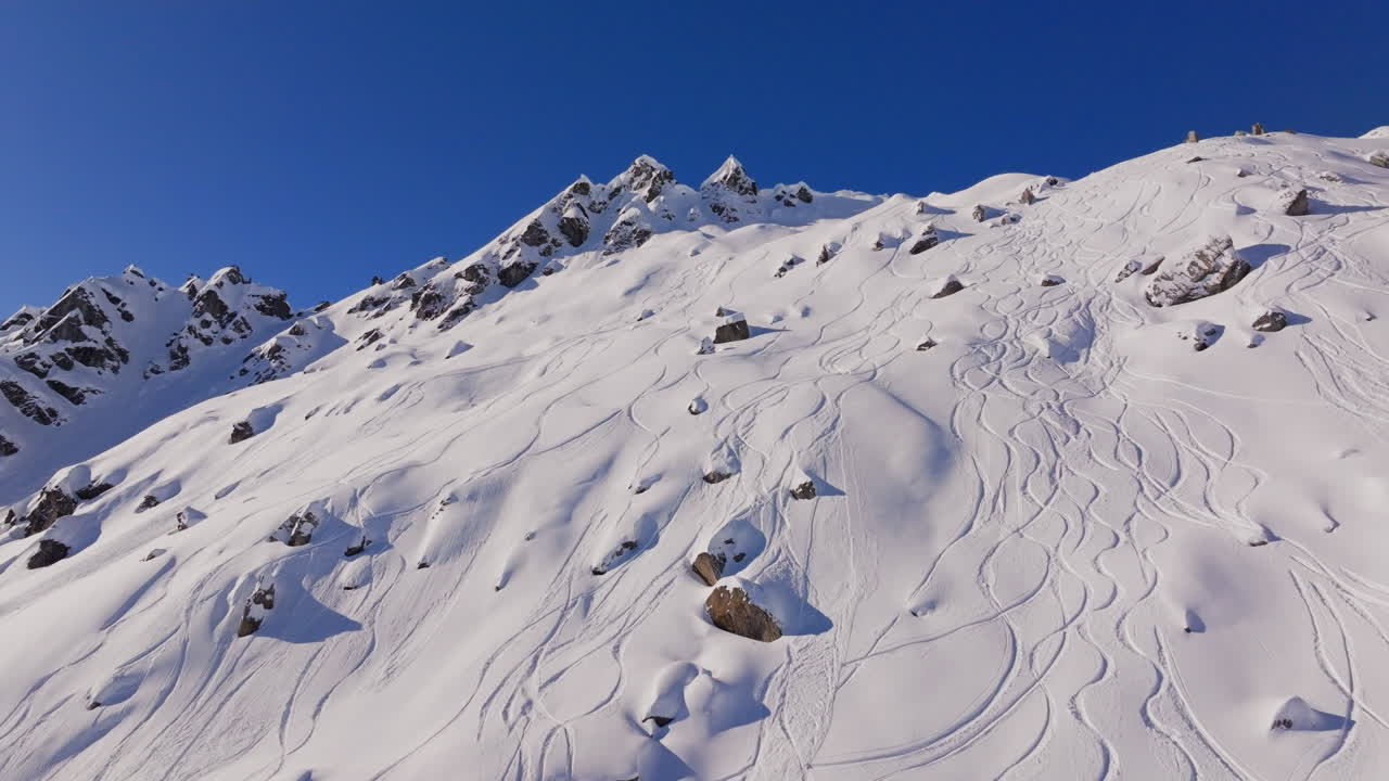 Aerial footage of the iconic freeride paradise of Verbier on a stunning bluebird day. Snow-covered peaks, wide open faces, and legendary off-piste terrain under clear alpine skies