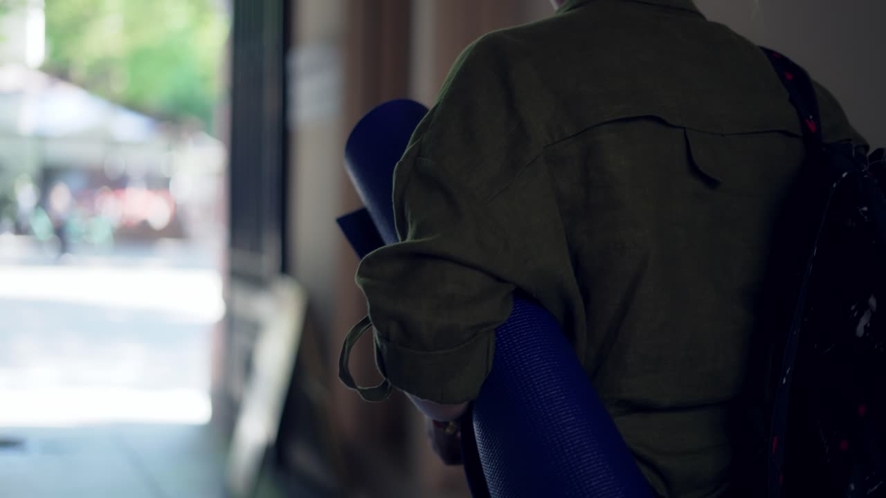 ヨガマットを背負った認識できない女性がアーチを通過します