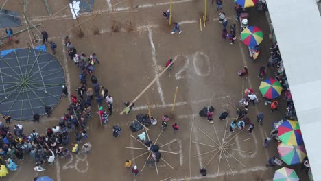 People-walking-with-big-bamboo-stick-at-Sumpango-Kite-Festival,-aerial