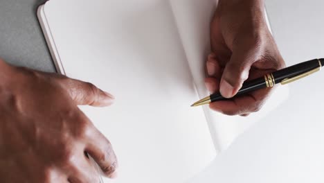 Close-up-of-hand-writing-with-pen-on-book-with-copy-space-on-white-background-in-slow-motion