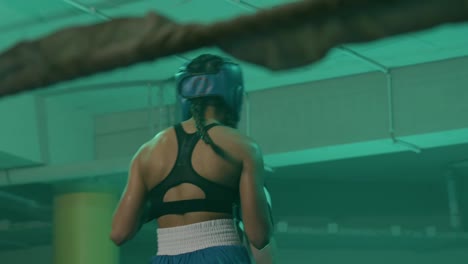 two female boxers in helmets and boxing gloves fighting in ring at gym