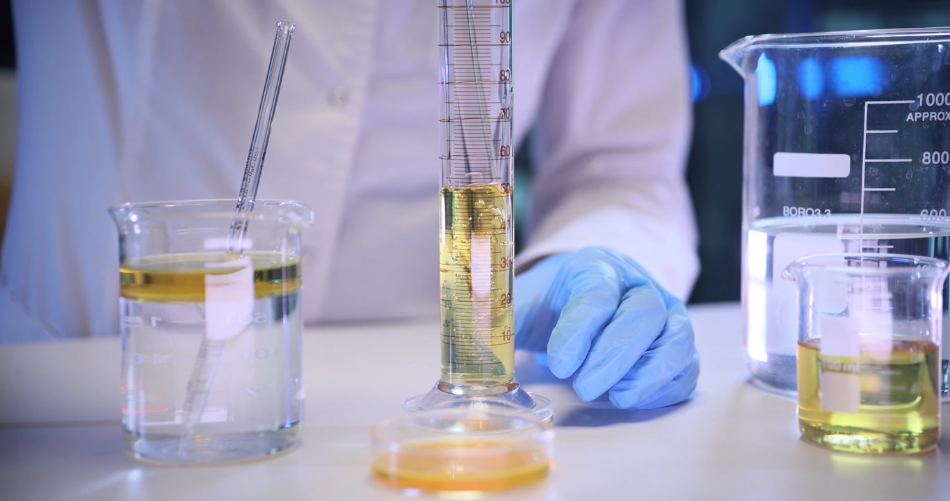 Scienziato misura un liquido giallo in un cilindro di vetro in laboratorio.