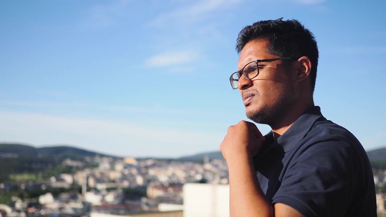 Thoughtful Man Looking at City View from Rooftop