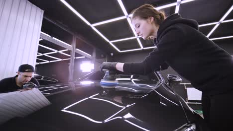 trabajador pulir un coche negro. detalles del coche - mujer están usando maquinaria pulidores de automóviles mantenimiento para eliminar marcas reparación de acuerdo con la superficie de la pintura del coche antes de contin