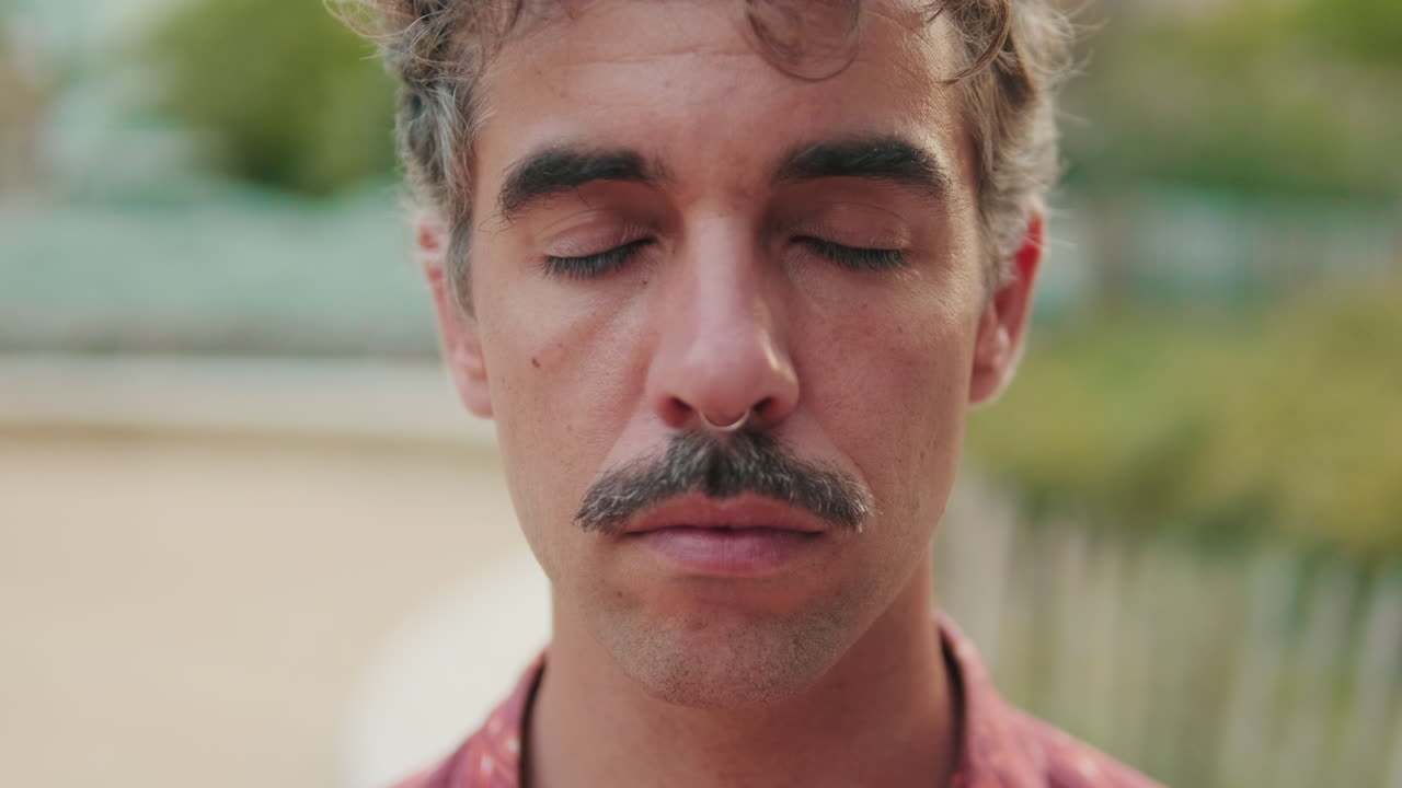 Primer plano de hombre con bigote abriendo los ojos y sonriendo