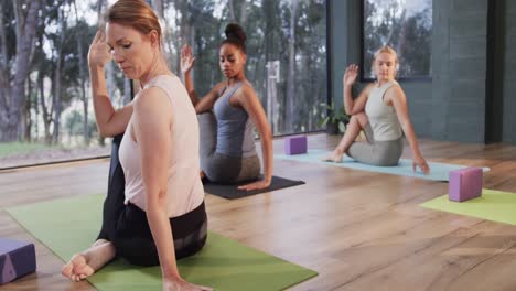 Focused-diverse-women-stretching-together-on-mats-in-yoga-class-with-female-coach,-slow-motion