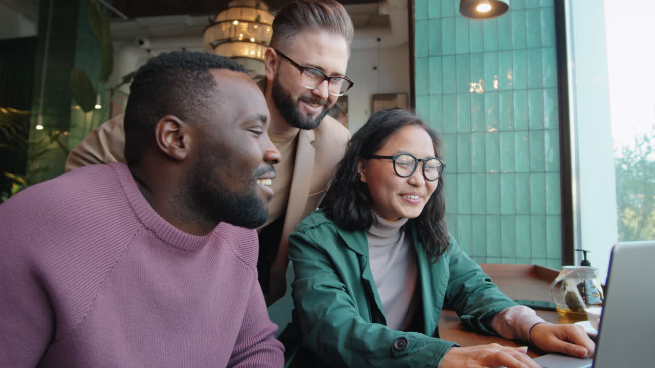 Diverse Colleagues Working on Laptop and Speaking in Cafe