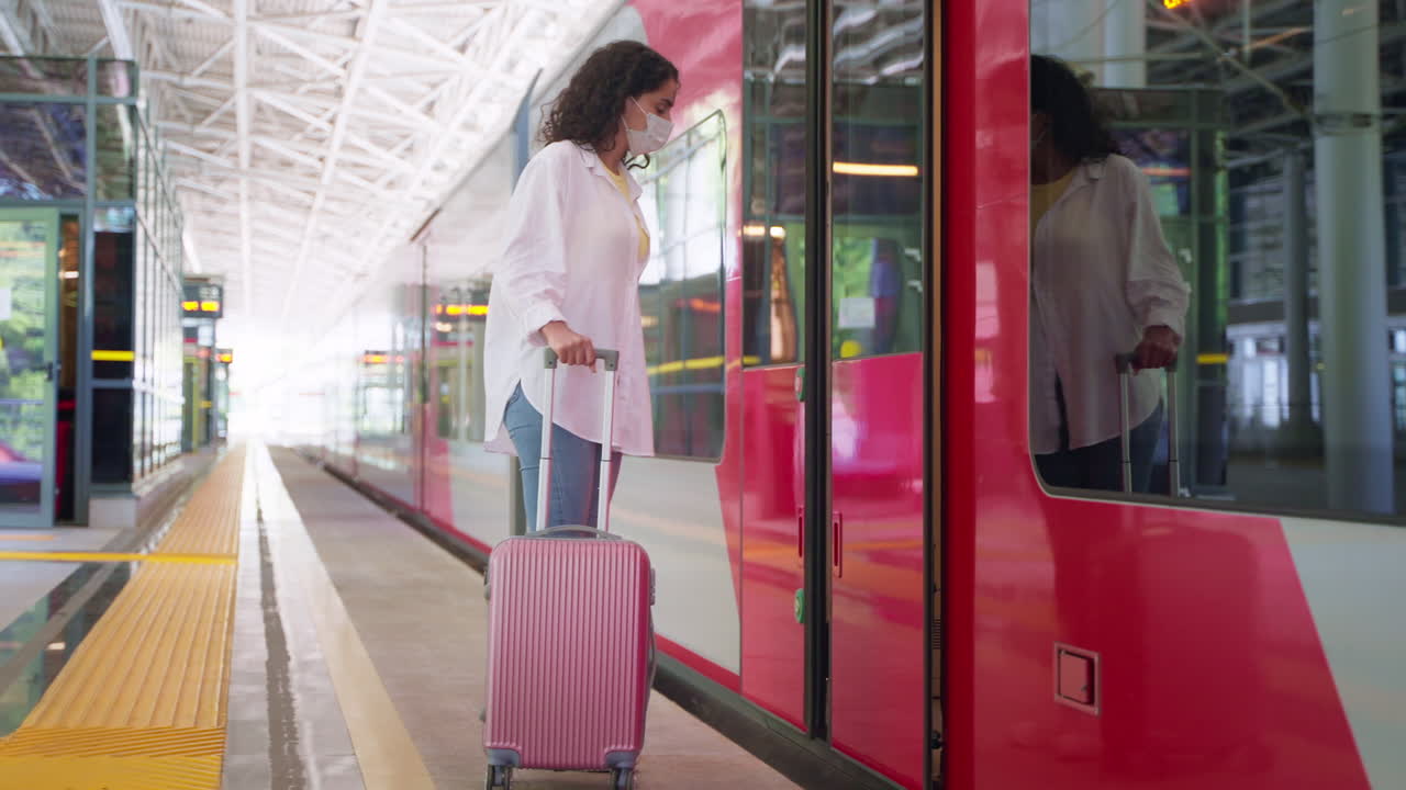 una mujer con una maleta subiendo a un tren, usando una máscara facial durante la pandemia.