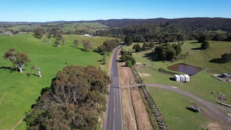 Carretera-A-Través-De-Tierras-De-Cultivo-Verdes-Aéreas-Con-Conducción-De-Automóviles-A-Través-De,-Australia