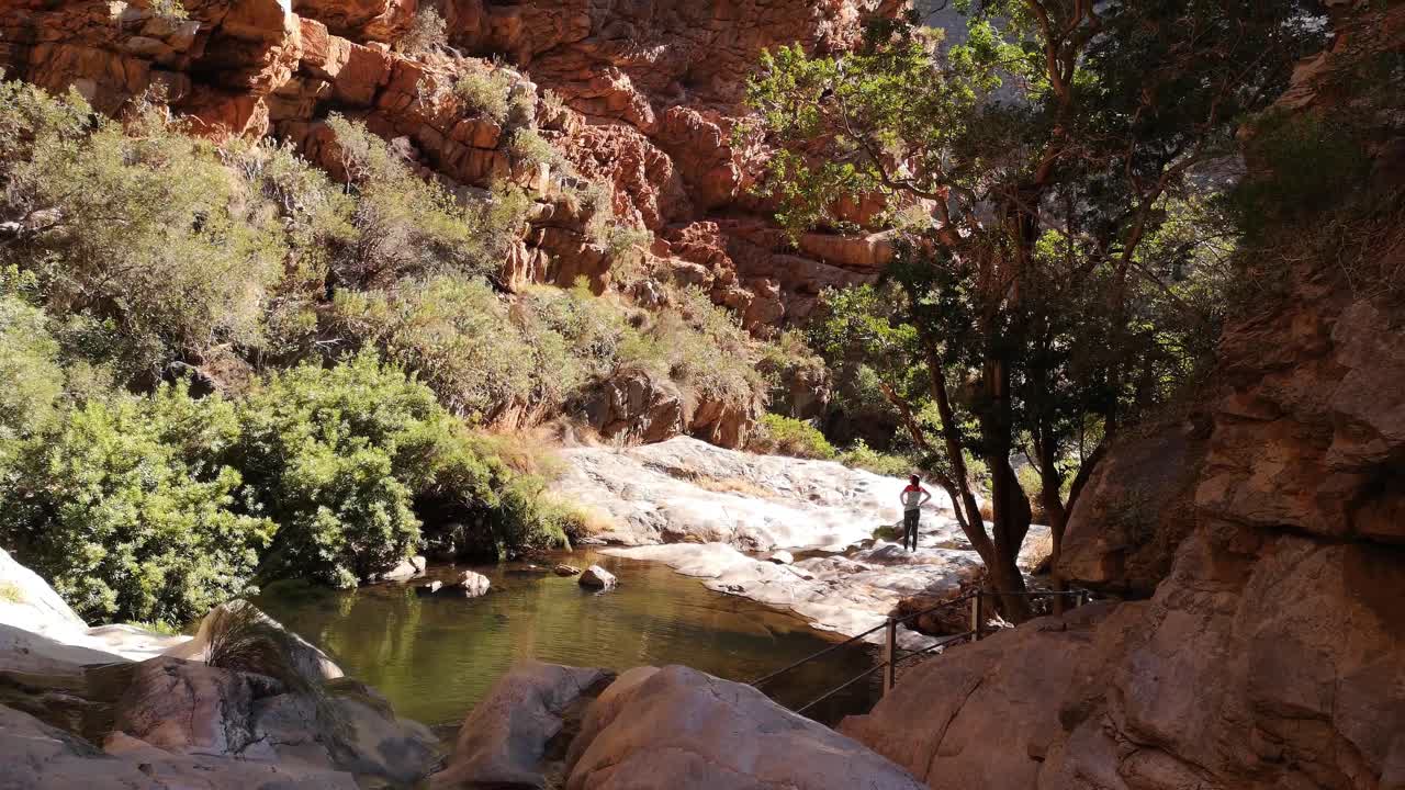 Water pools with woman looking out to the distance. Filmed at the beautiful Meiringspoort waterfalls and pools in the Western Cape area of South Africa