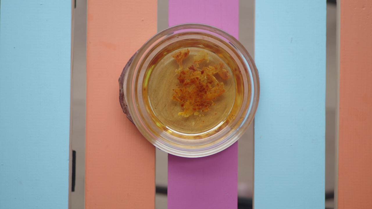 Saffron Infused Oil in a Jar on a Colorful Wooden Background
