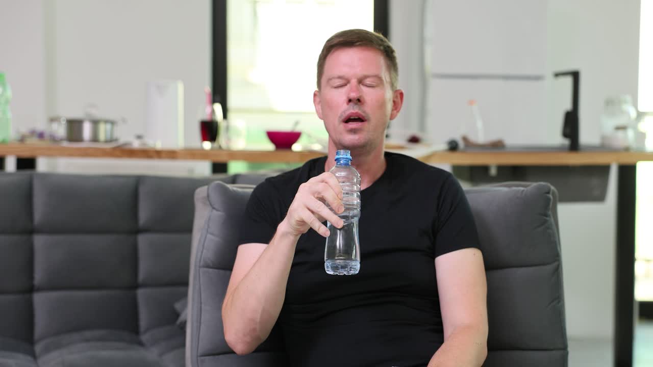 소파에서 물을 마시는 남자